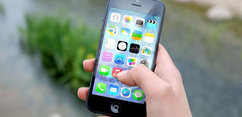 Рука с телефоном, на экране - значки приложений