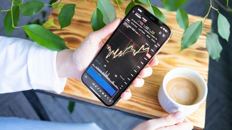 Рука со смартфоном, на котором график роста акций