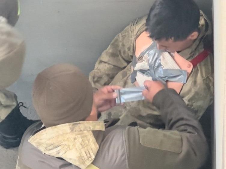 Солдат накладывает повязку сослуживцу