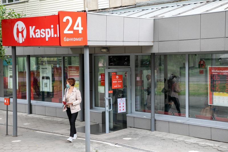 Женщина выходит из отделения Kaspi.kz