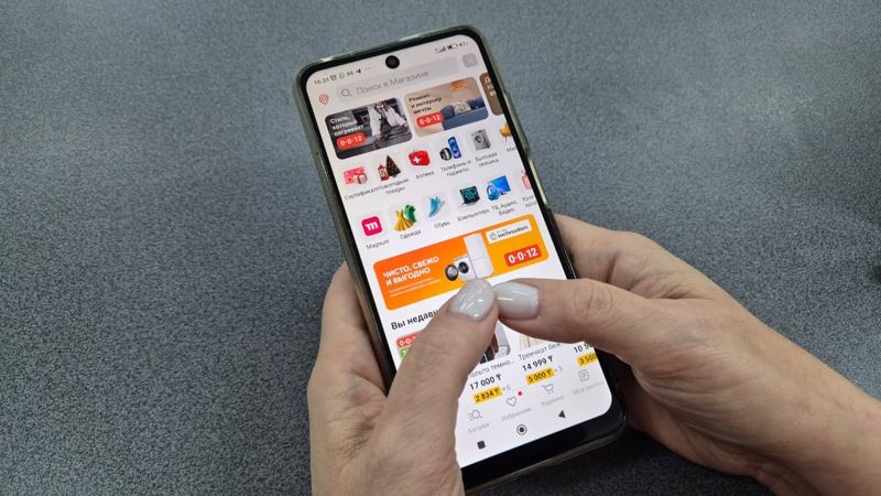 Телефон в руках с открытым приложением маркетплейса.