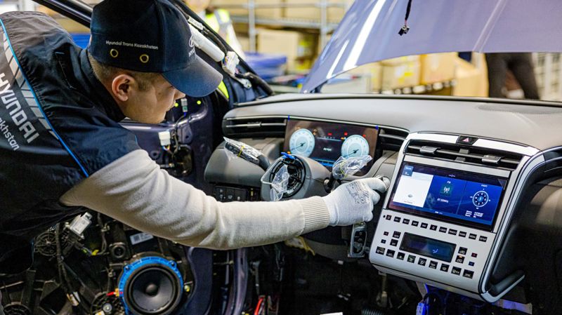 Рабочий устанавливает мультимедийную систем в автомобиль