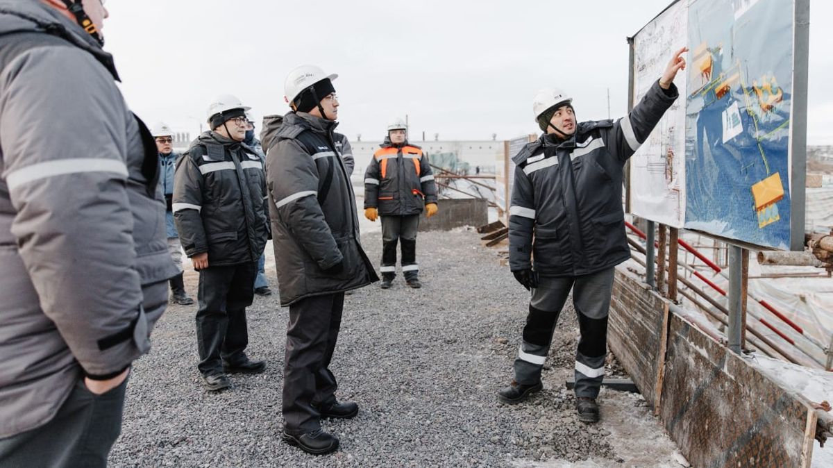 Шухрат Ибрагимов на предприятии, у стенда с планами ERG