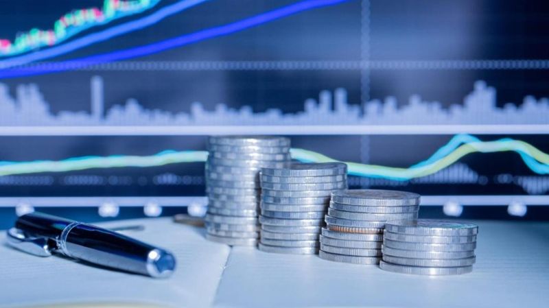 Стопки монет, ручка на столе, дивиденды, акции, выплаты