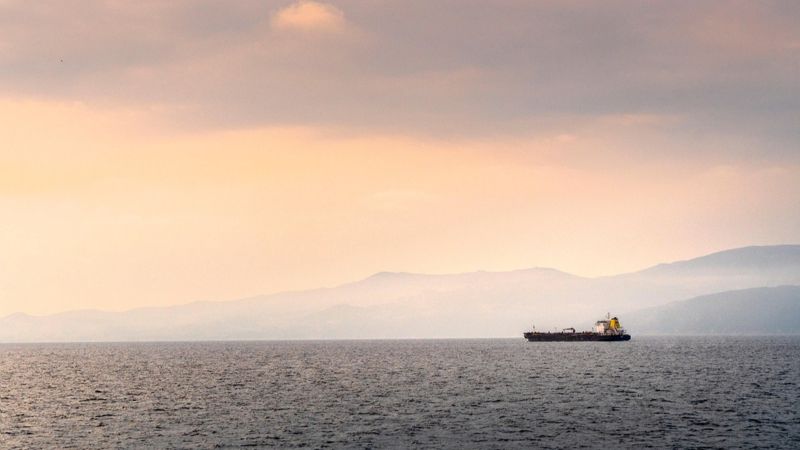 Танкер на воде на фоне гор.